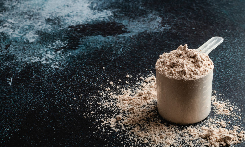 Top view whey protein scoop on dark background, copy space